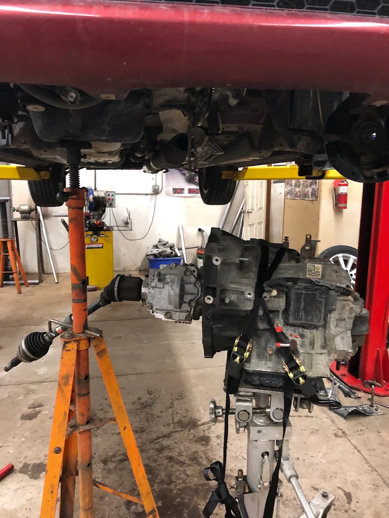 Gearbox and driveshaft lowered on a jack under a vehicle on the hoist